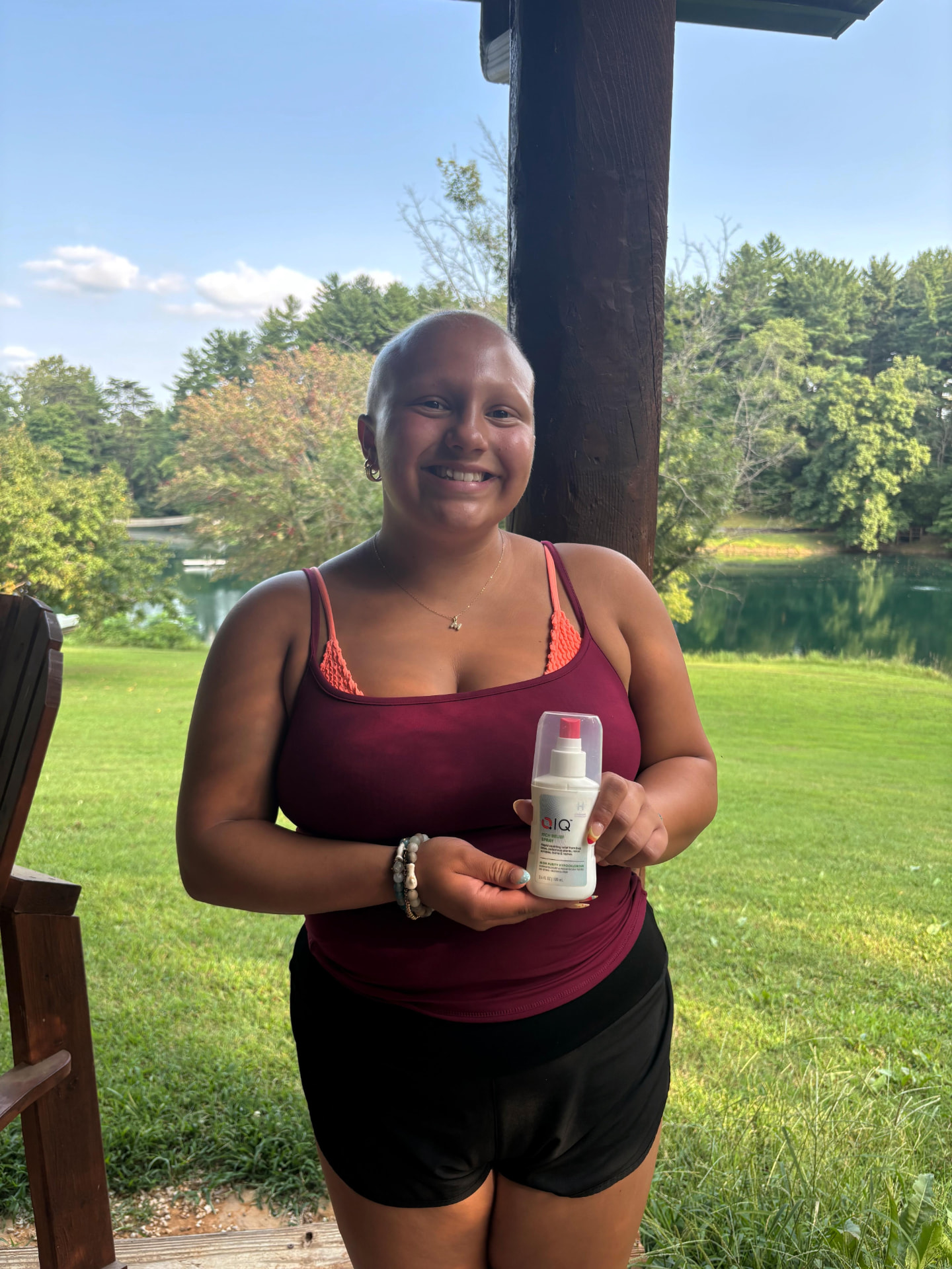 CAP camper holding her QIQ Skin Savior spray beside the camp lake