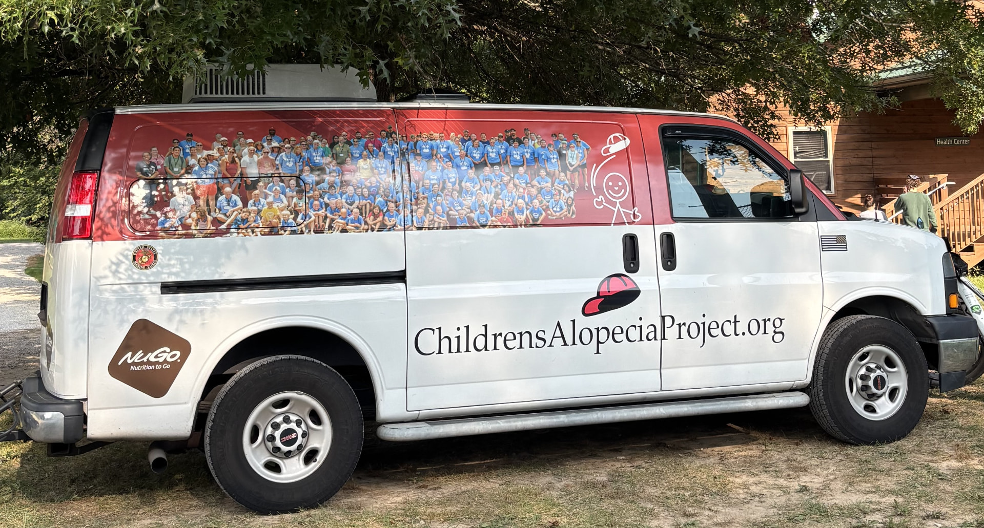 The Children's Alopecia Project tour van, wrapped with a photo of Alopeciapalooza campers and ChildrensAlopeciaProject.org lettering